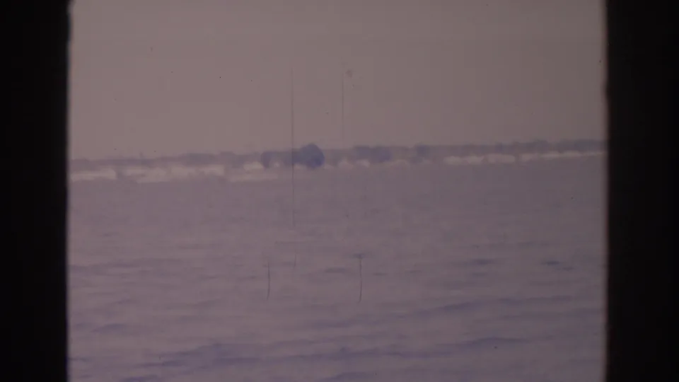 1962 Florida 8mm frame showing rippled water and a faint far shoreline through dark vertical edges.