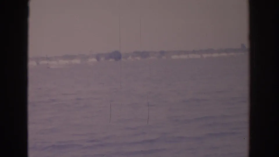 Faded 1962 Florida waterfront view with soft focus, rippled water, and a distant tree-lined shore.