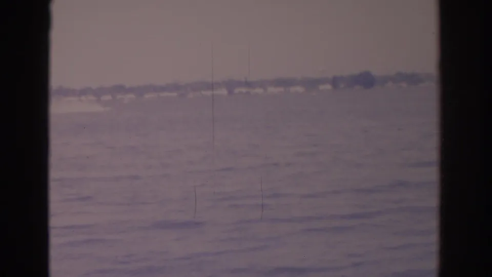 1962 Florida home-movie frame with a broad water surface and hazy shoreline under faded color.