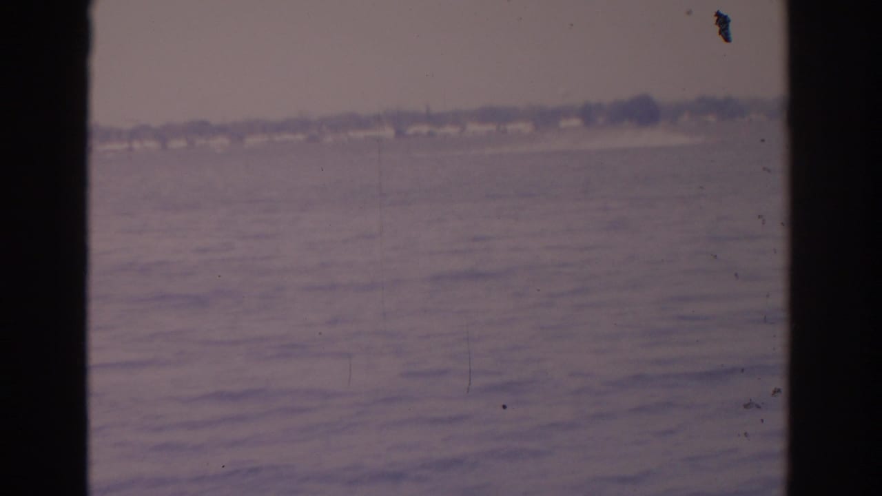 Calm ocean water with a faint distant shoreline seen between dark vertical edges.