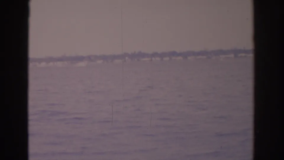 The final 1962 Florida frame holds on rippled ocean water and a faint shoreline beneath an overcast sky, with dark vertical framing.