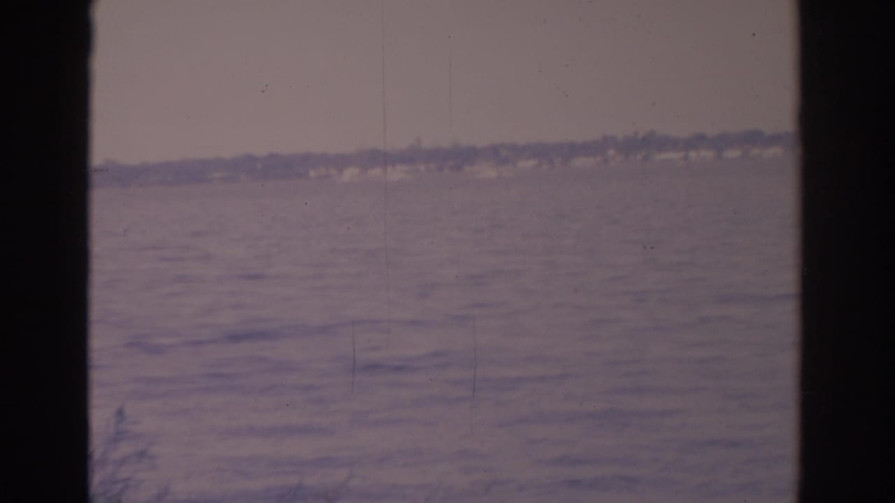 Lake water seen through dark vertical window edges with a faint distant shoreline.