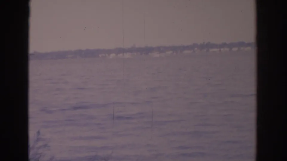 1962 Florida 8mm frame showing lake water, a hazy far shoreline, and dark window framing at the sides.