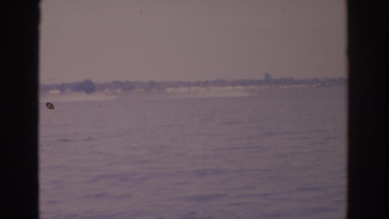 Broad water surface with hazy shoreline and dark vertical frame edges.