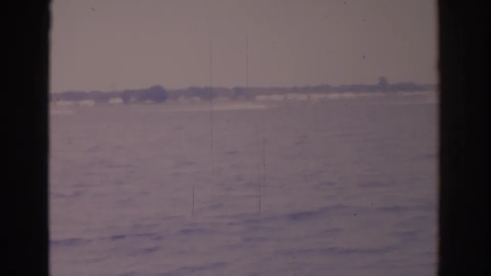 1962 Florida lake cutaway with soft faded color, distant shoreline, and window edges framing the water view.