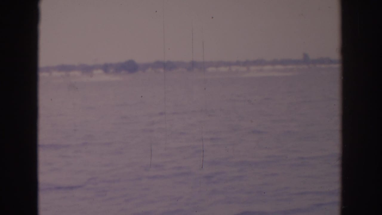 1962 Florida 8mm frame appears to show a pale open water or horizon view, softened by film grain and vertical gate shadows.