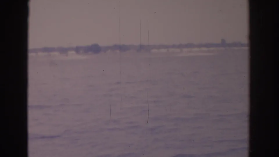 1962 Florida 8mm frame appears to show a pale open water or horizon view, softened by film grain and vertical gate shadows.