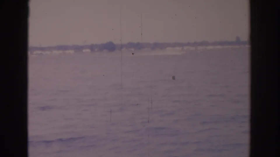 1962 Florida home-movie frame with a hazy open horizon or water view, visible film grain, and dark 8mm gate borders.
