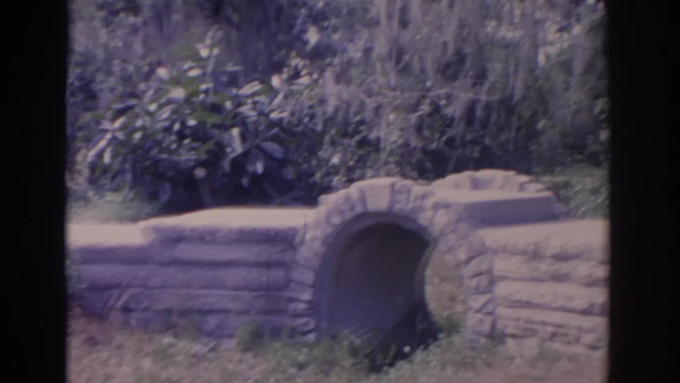 1962 Florida 8mm frame of the small arched stone bridge after the woman has moved out of view.