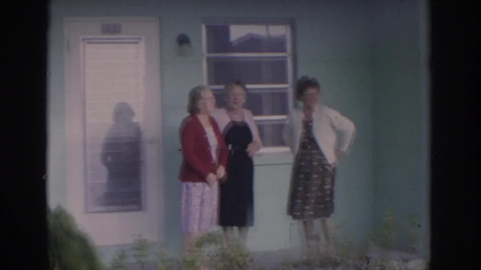 Three adult women stand close together on a Florida porch in 1962, framed by a screened door, window, and pale green exterior wall.