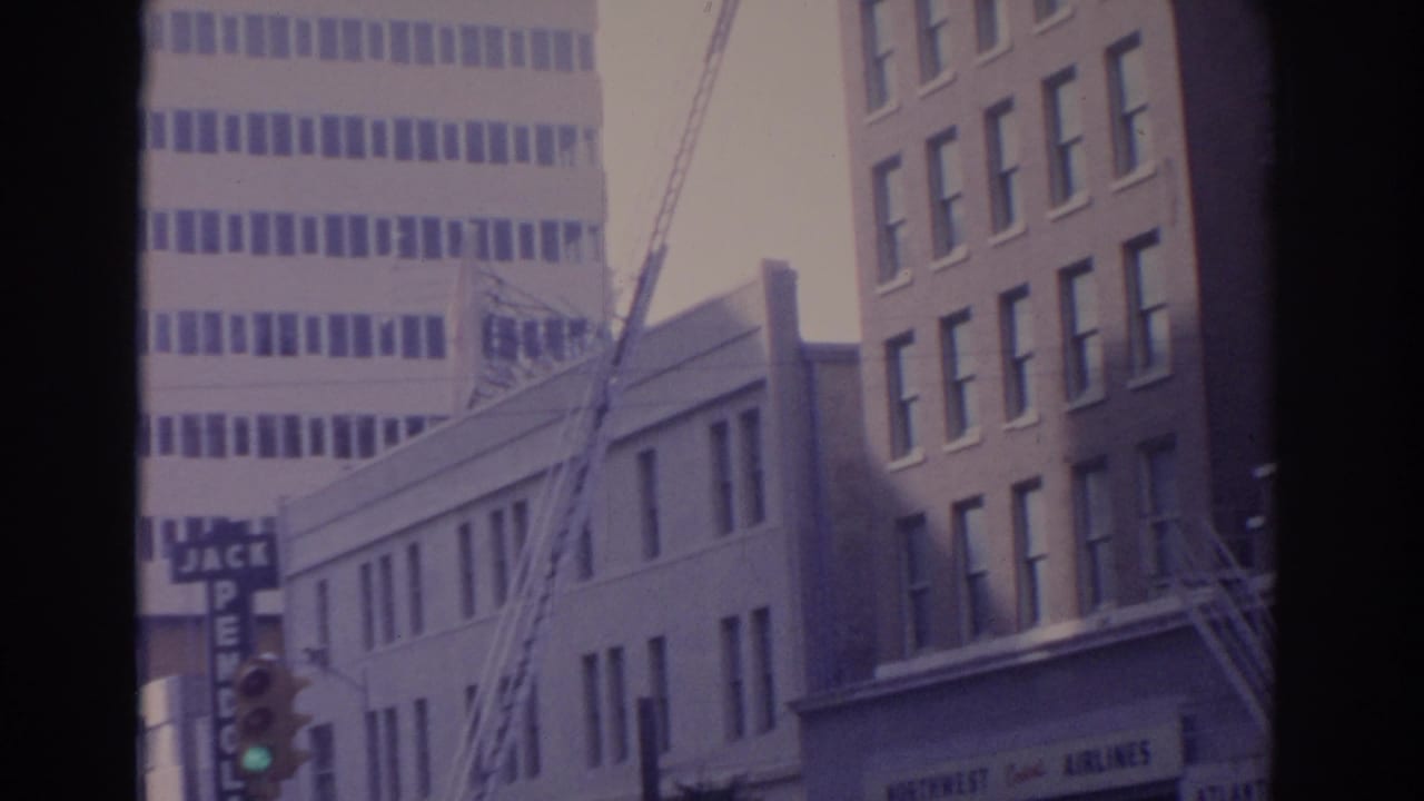 Downtown buildings with a tall ladder, traffic signal, and partial Jack Pendola sign.