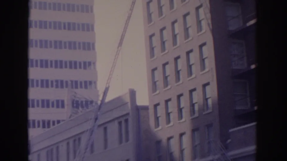 1962 Florida urban frame showing office facades, a ladder angled upward, and partial Northwest Airlines signage at street level.
