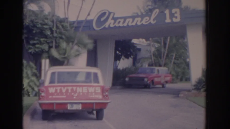 1962 Florida 8mm frame with the Channel 13 sign above a driveway and a red WTVT NEWS station wagon in the foreground.