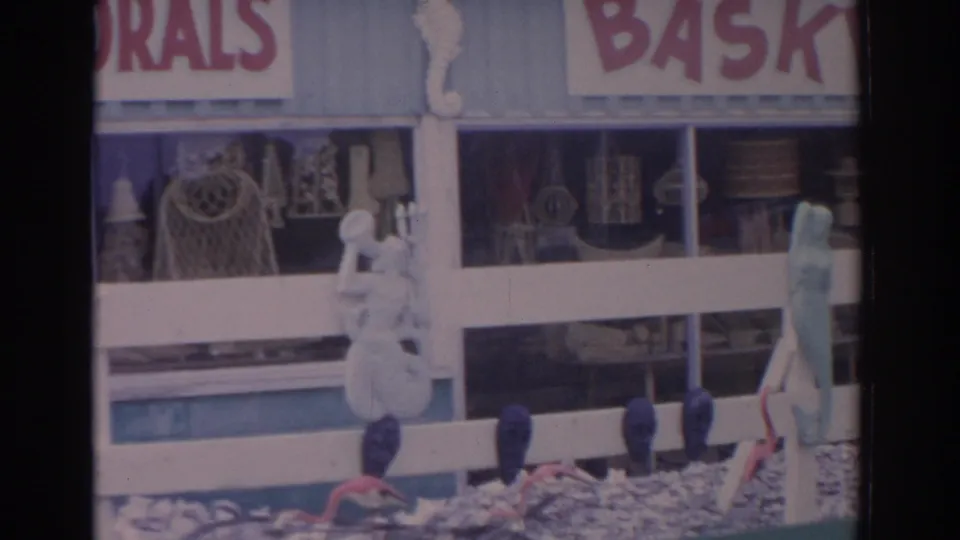 8mm frame of the Florida shop display with partial CORALS lettering, white rail, seahorse ornament, lamps, and baskets.