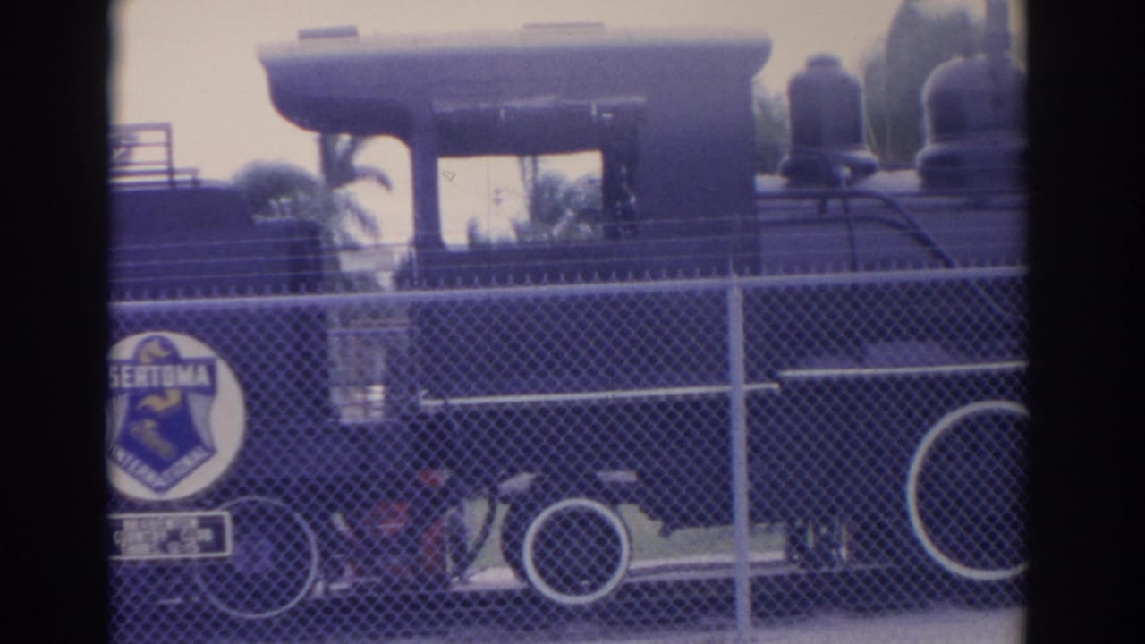 Steam locomotive behind a fence with a visible Sertoma International emblem on the side area.
