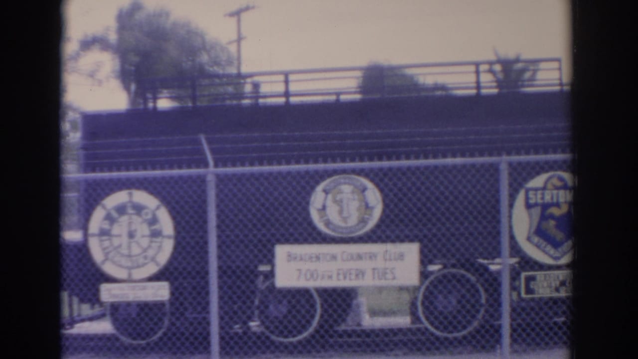 Fence line with circular club emblems, Bradenton Country Club sign, and bicycle wheels.