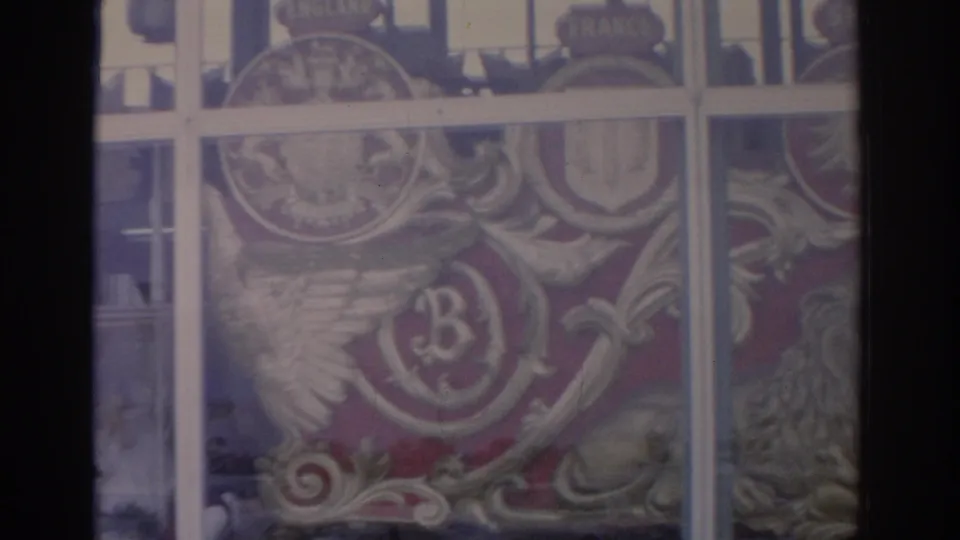 1962 Florida home-movie frame showing ornate painted crests, a lion form, and country-name plaques behind a window grid.