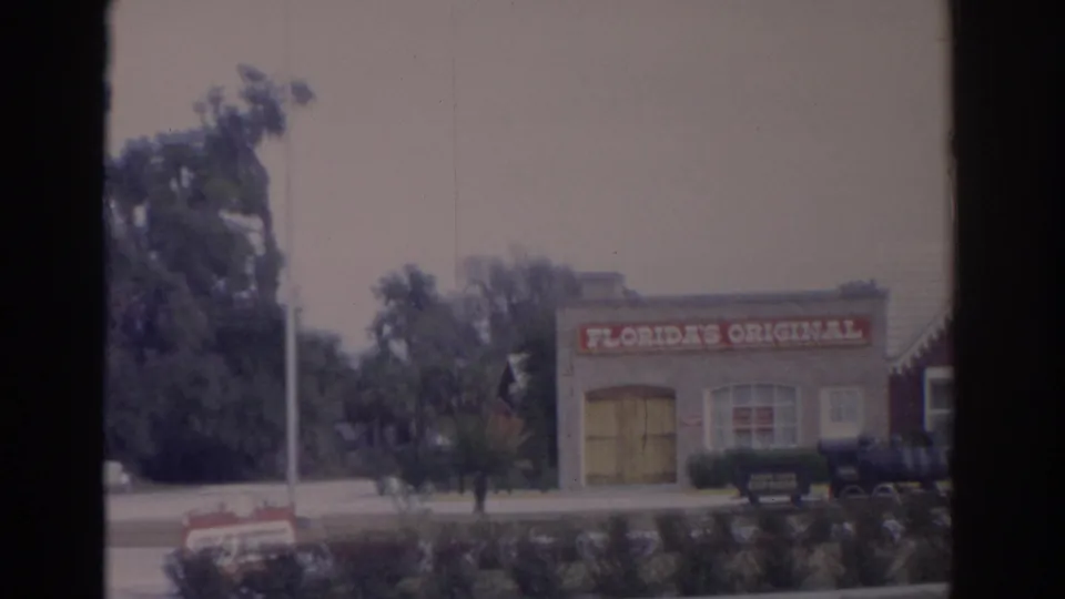 Florida attraction building labeled Florida's Original, seen across a roadway with trees and a small display area in front.