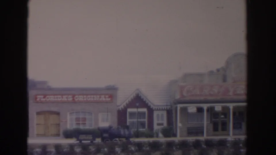 Final frame of the 1962 Florida attraction frontage with the Florida's Original sign, storefronts, hedges, and a small train display.