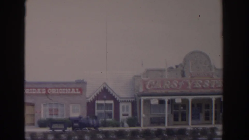 1962 Florida 8mm frame showing a roadside commercial facade with Florida's Original lettering and Cars of Yesterday signage.