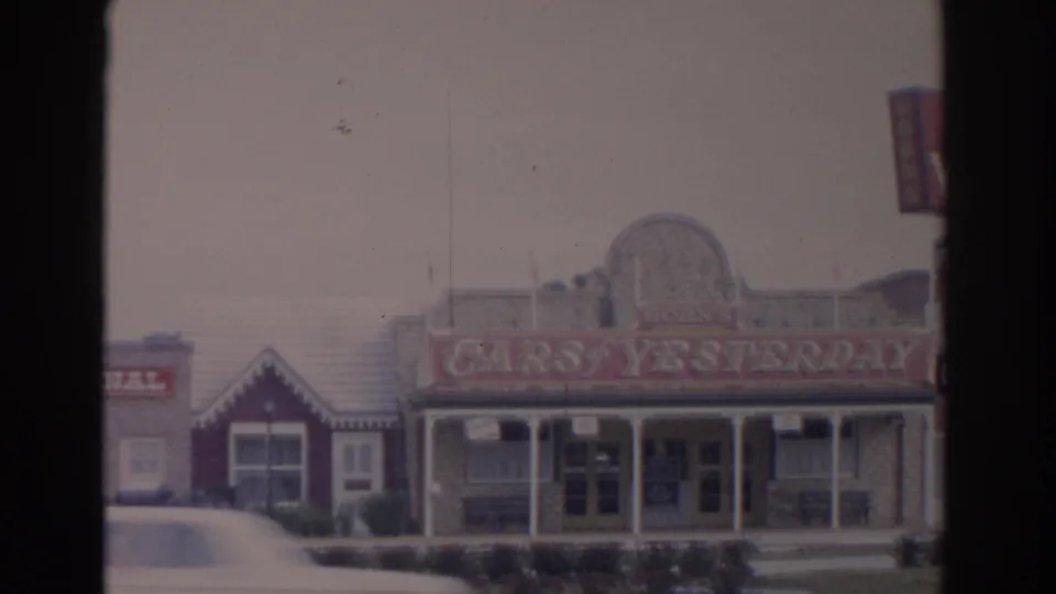 1962 Florida exterior view of the Cars of Yesterday facade, with a small neighboring storefront and sidewalk area.