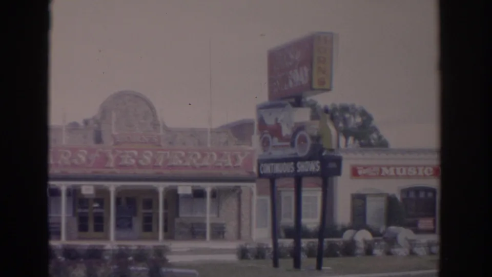1962 Florida 8mm frame showing a roadside attraction facade with Cars of Yesterday text and a red-and-yellow Music Fair sign.