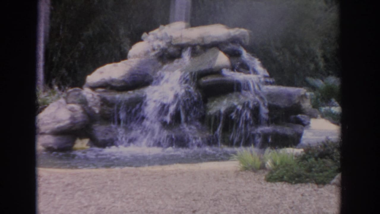 1962 Florida garden footage with a closer view of water cascading over stacked rocks into a pond.
