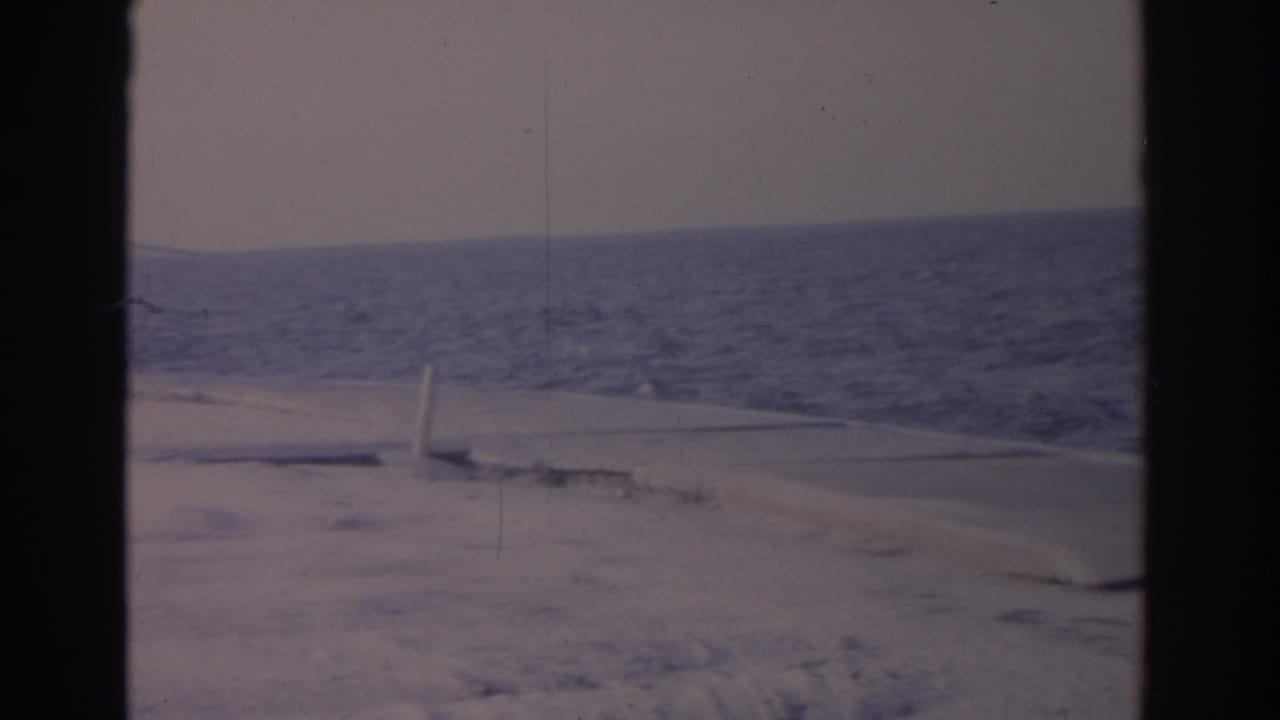 Snow-covered beach and ocean horizon seen through dark 8mm frame edges.