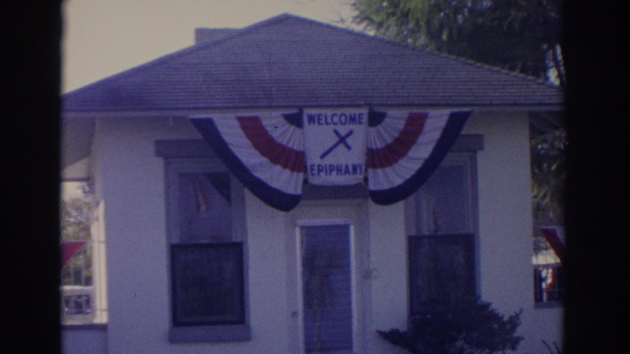 Florida 1962 frame of a small building decorated with patriotic bunting and a WELCOME EPIPHANY sign with a cross.