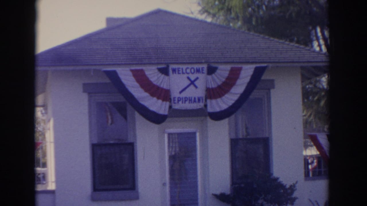 Close 1962 Florida home-movie view of a building facade with windows, bunting, and a WELCOME EPIPHANY sign.