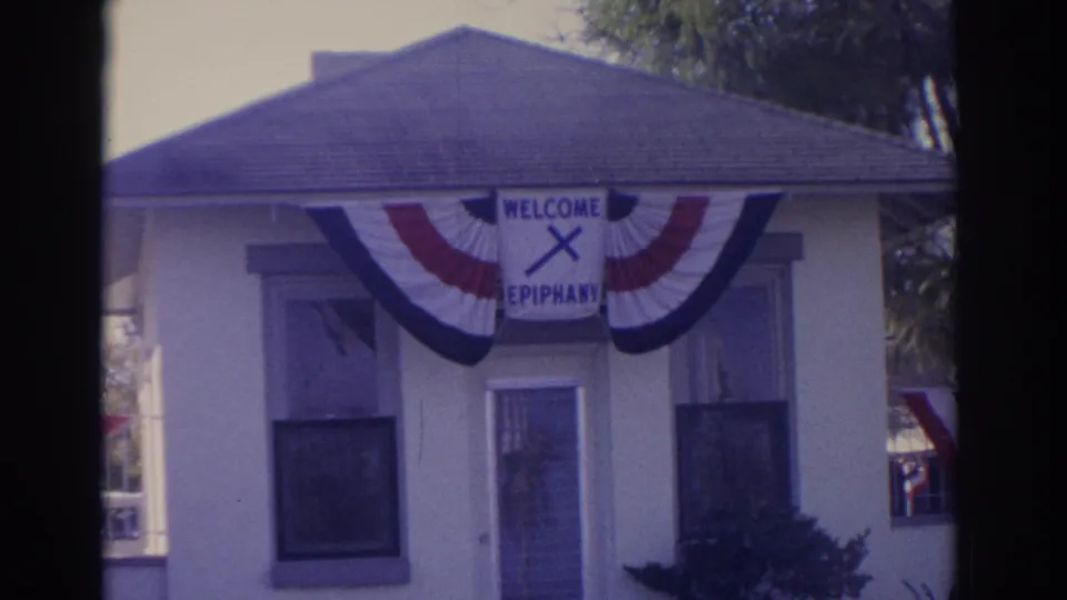 Final 1962 Florida frame showing the same decorated building with bunting, windows, and the WELCOME EPIPHANY sign.