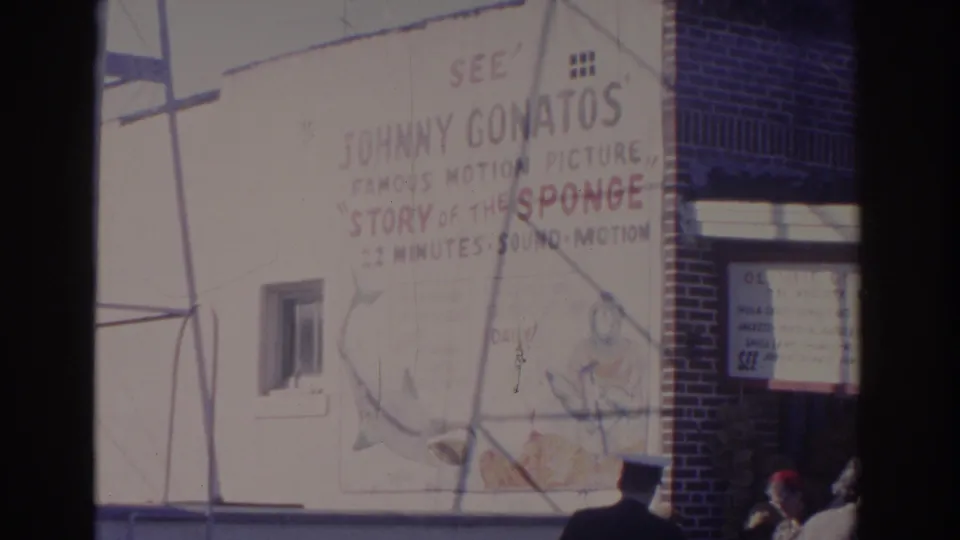 1962 Florida street view with a large painted Story of the Sponge advertisement and people partly visible near the building entrance.