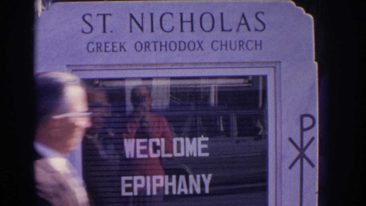 A man passes in front of the St. Nicholas Greek Orthodox Church sign, with welcome epiphany lettering visible behind him.