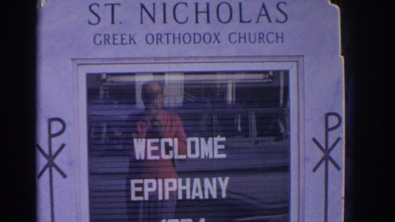 The St. Nicholas Greek Orthodox Church sign fills the frame, with welcome epiphany letters and reflected street detail in the glass.
