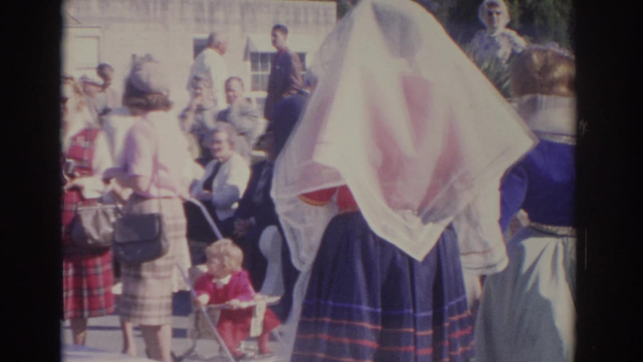 1962 Florida home-movie view of people gathered outside a church, including formally dressed women and a child near a stroller.