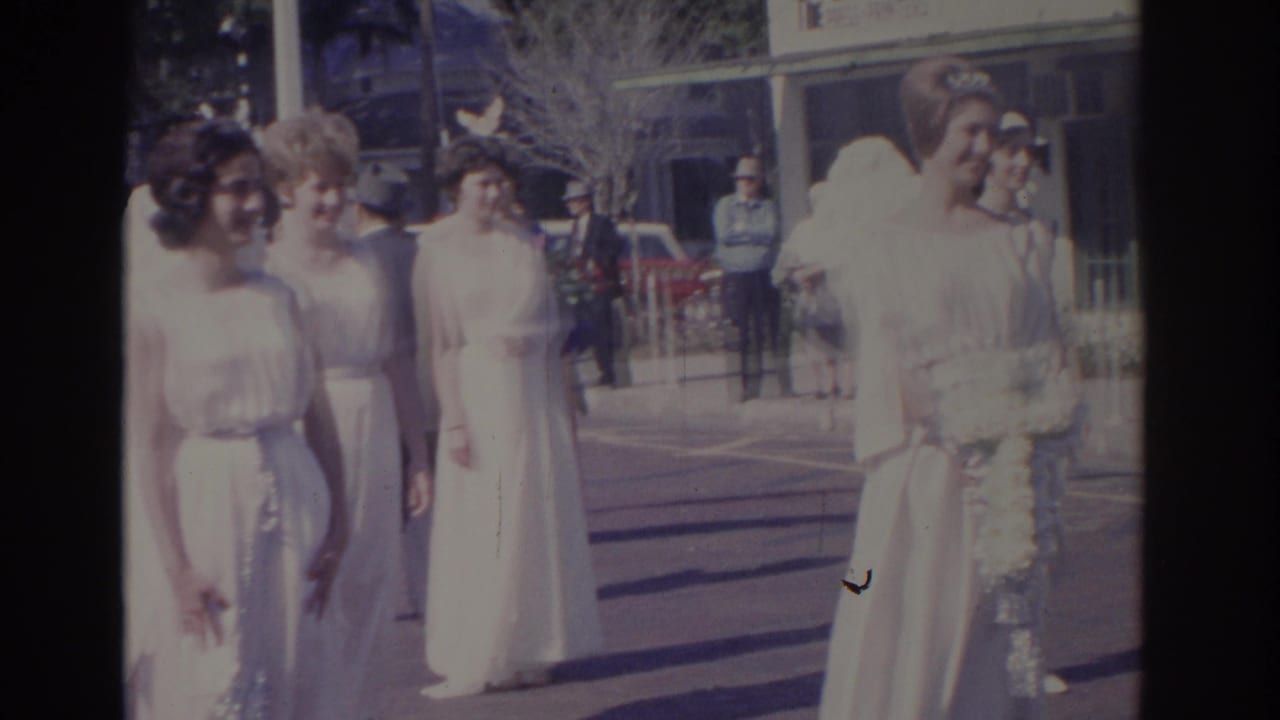 Young women in white gowns and angel wings stand on a downtown street.