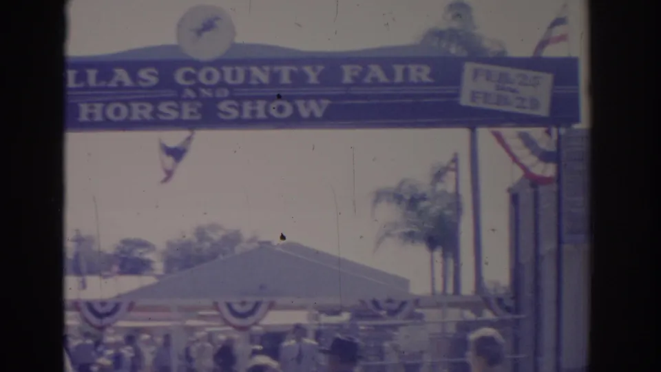 1962 Florida home-movie frame showing a county fair and horse show entrance sign with bunting and visitors below.