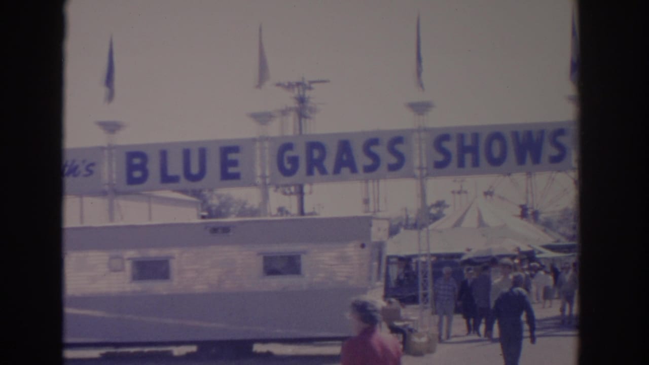 1962 Florida 8mm frame showing visitors walking beneath the Blue Grass Shows banner toward a tented fairground area.