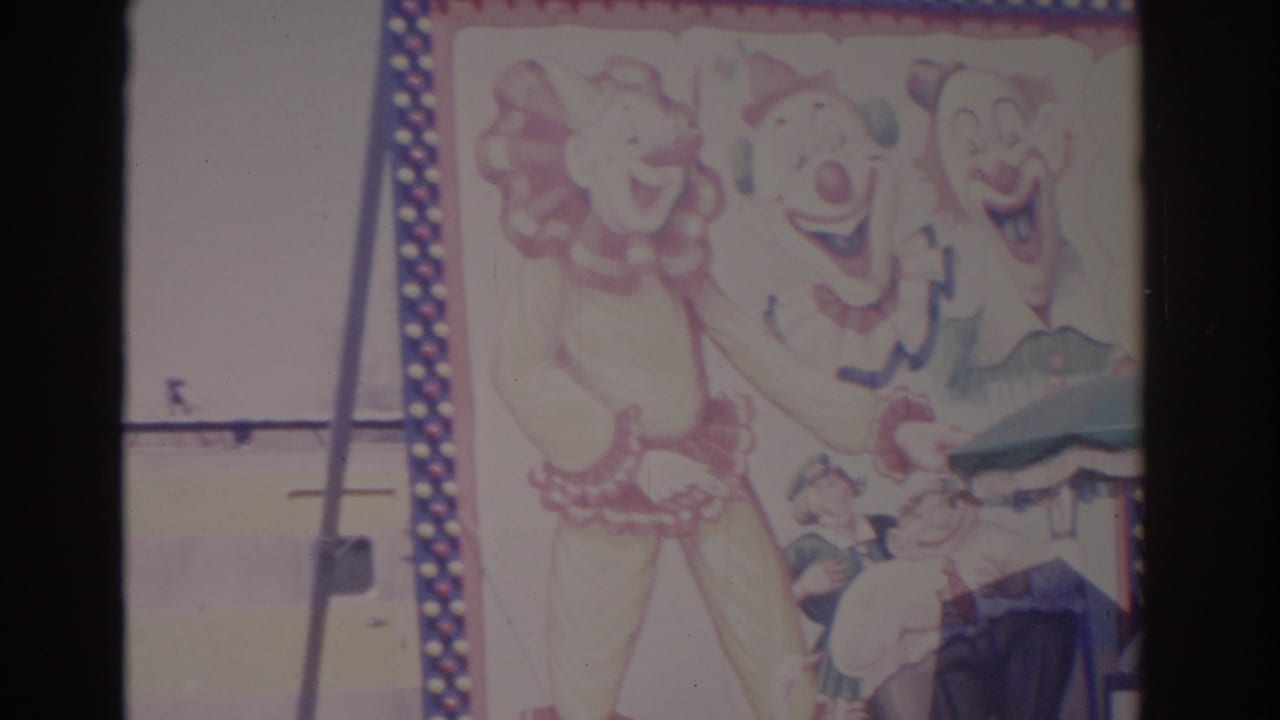 Carnival sign with painted clown figures above a booth and awning.