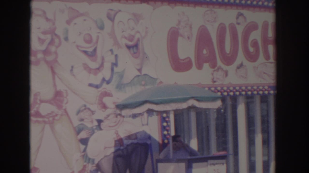 1962 Florida 8mm frame showing the red Laughterland lettering, a painted clown figure, a green awning, and a person partly visible near the booth.