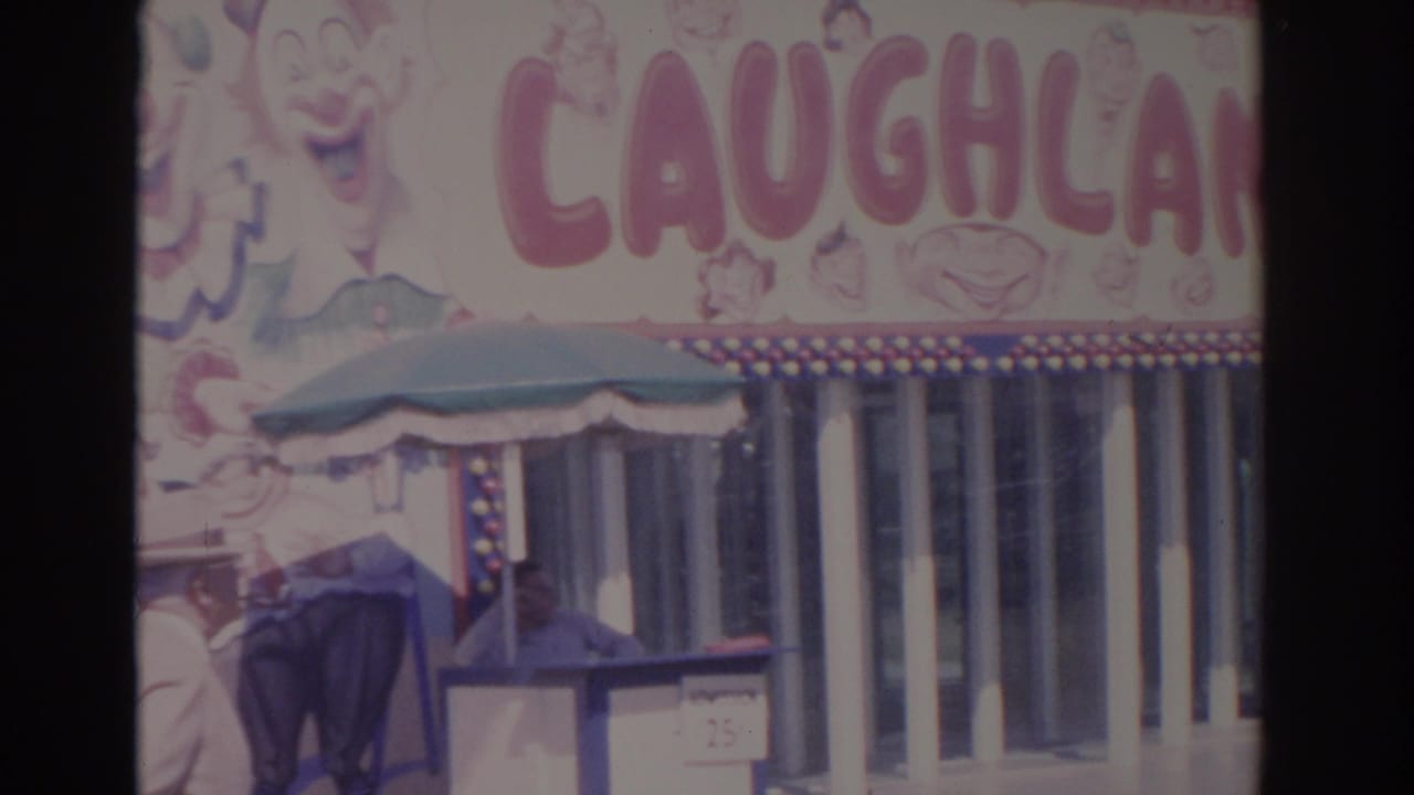 1962 Florida home-movie frame with the Laughterland sign, booth windows, green awning, and a partially visible person at the lower edge.