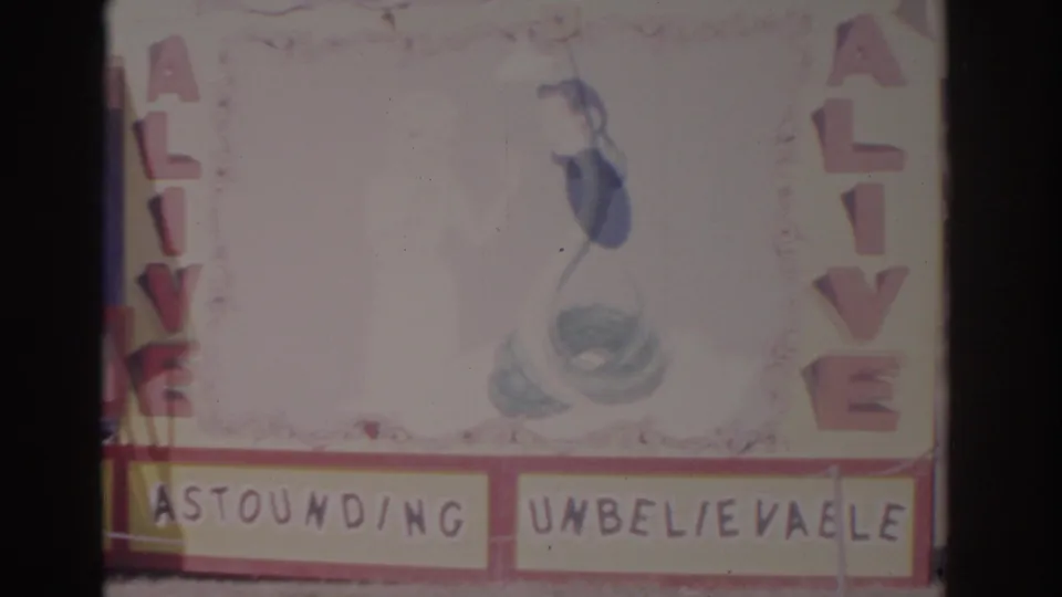 1962 Florida 8mm frame of a sideshow wall with painted mermaid art, vertical ALIVE lettering, and Astounding Unbelievable panels.