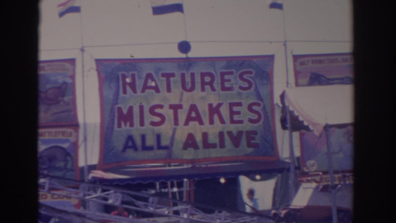 1962 Florida carnival footage shows the NATURES MISTAKES ALL ALIVE banner with fairground structure and a small passerby below.