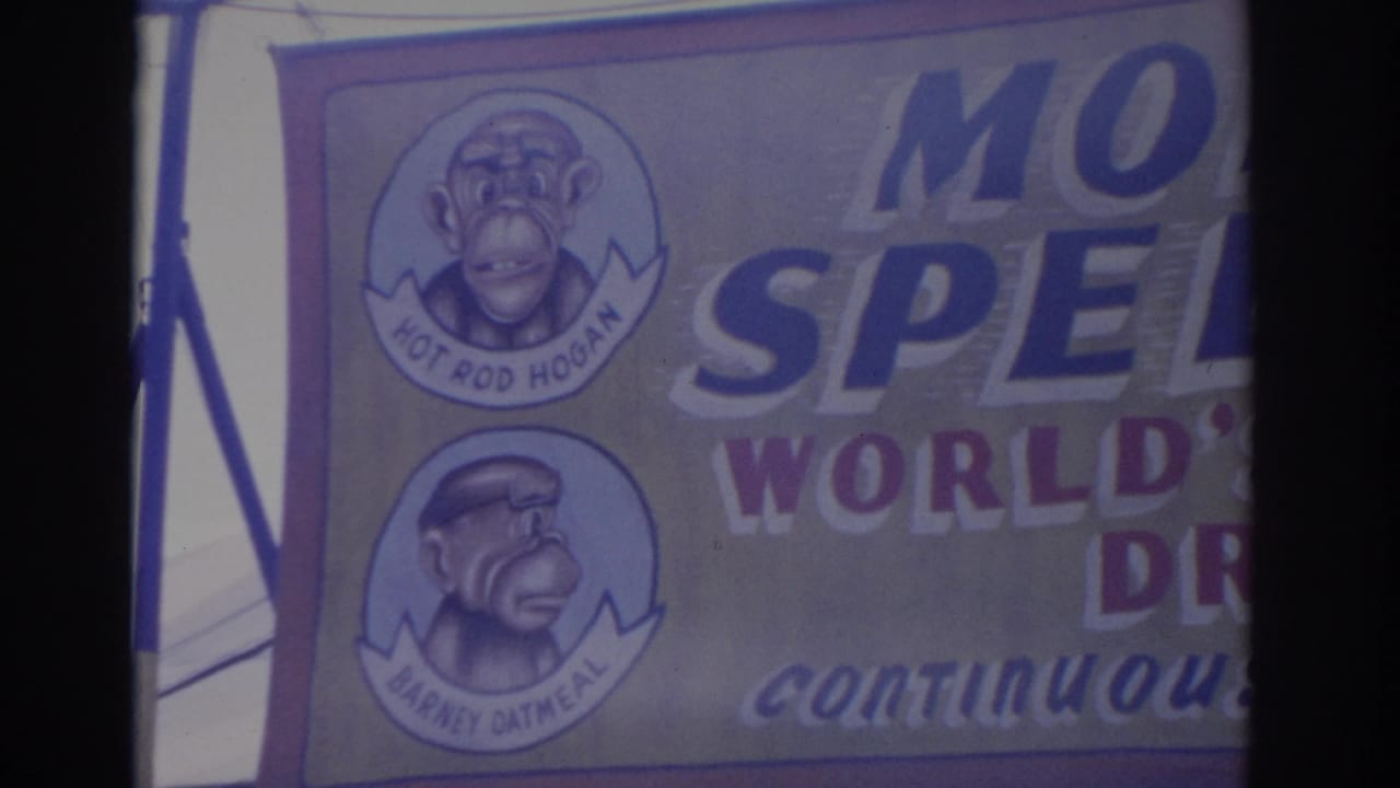 Florida 1962 home-movie frame showing a monkey-themed attraction banner with circular character portraits and large cropped lettering.
