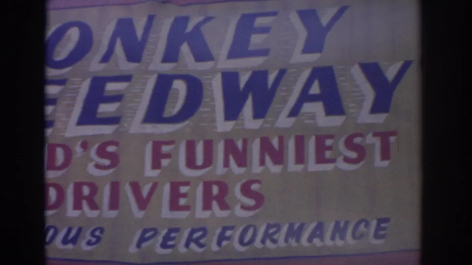 1962 Florida 8mm frame showing the lower left area of the Monkey Speedway sign, cropped around the large blue lettering.