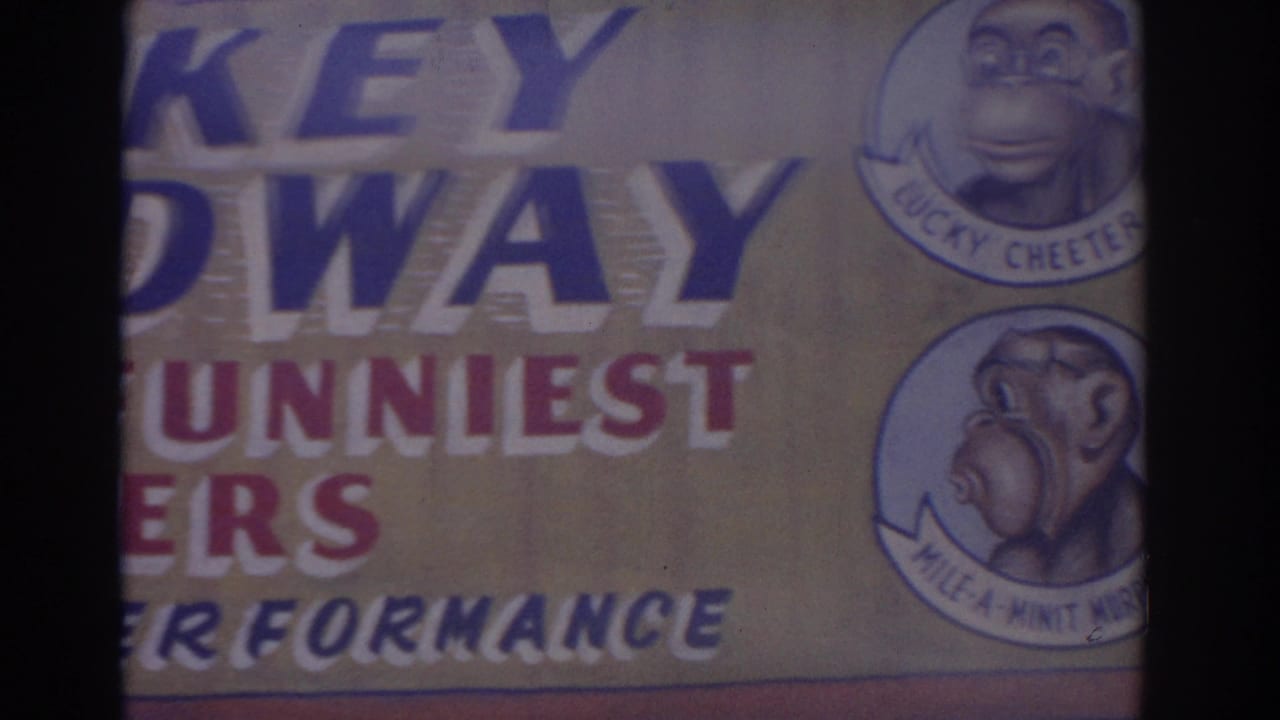 1962 Florida 8mm frame showing the lower right portion of the Monkey Speedway sign with two cartoon monkey character medallions.