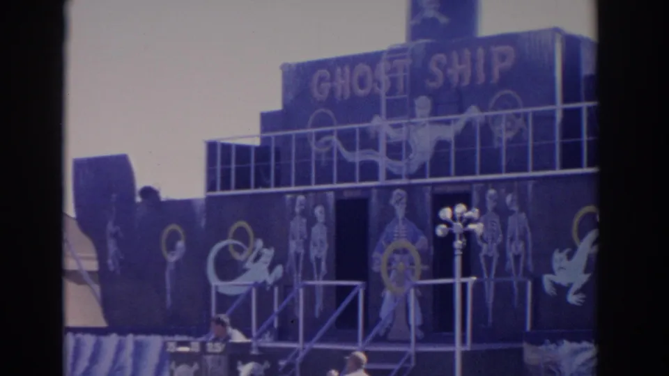 Florida 1962 home-movie frame centered on the Ghost Ship attraction, with skeletal paintings, railings and a dark blue boat facade.
