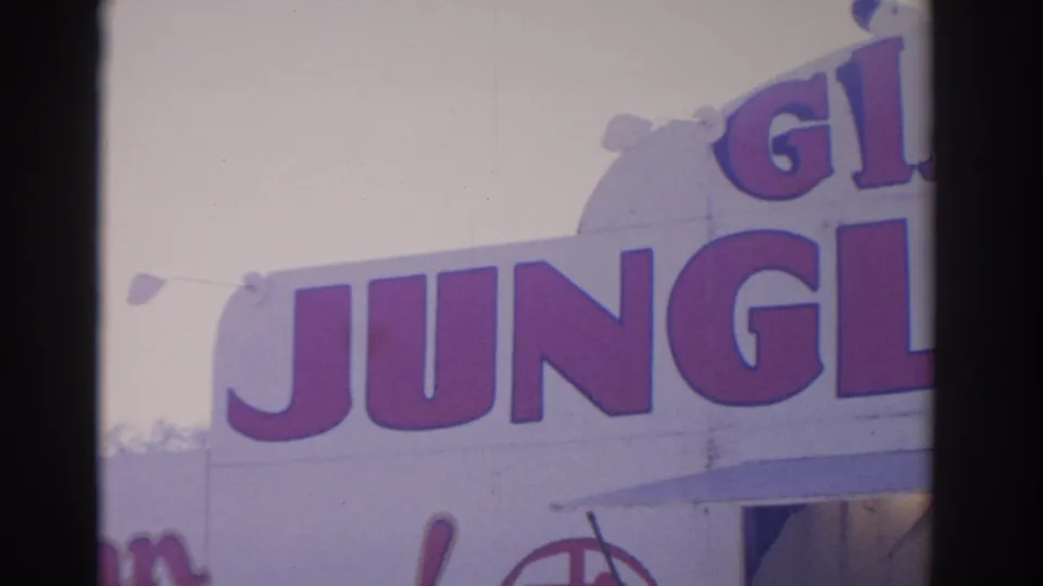 1962 Florida 8mm frame with oversized red Giant Jungle lettering on a bright carnival facade, partly cropped by the camera.