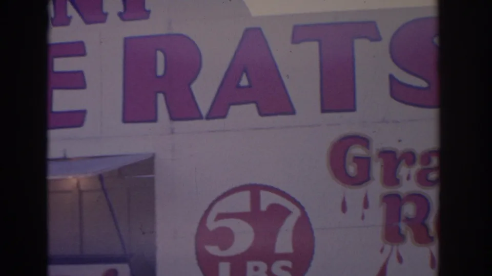 1962 Florida 8mm frame with partial ERATS lettering, a circular 57 mark, and cropped storefront details on a white commercial facade.