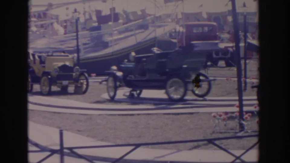 1962 Florida home-movie frame showing a dark antique-style ride car moving past a yellow car on a carnival attraction track.